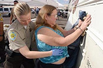 A Maricopa County Detention Officer frisks Peggy Simpson of Phoenix, Simpson was then loaded on a bus with other suspects at a staging area at Park Central.