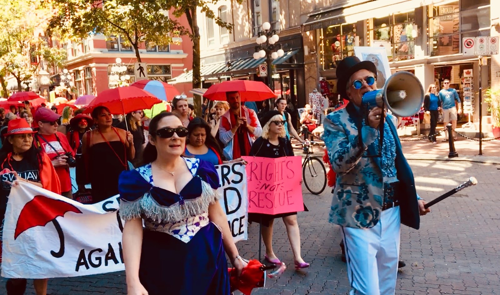 DeeJay and Chili Bean (holding SWUAV banner) and Triple-X's Kerry Porth (front left) and Andy Sorfleet (with bullhorn) lead the Red Umbrella March through Gastown. Vancouver, June 9, 2018. Photo: Elaine Ayres.